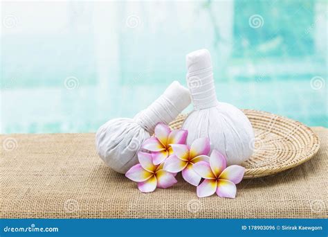 Thai Herbal Massage Ball With Plumeria Flower On Rattan Tray Over Blurred Blue Water Background