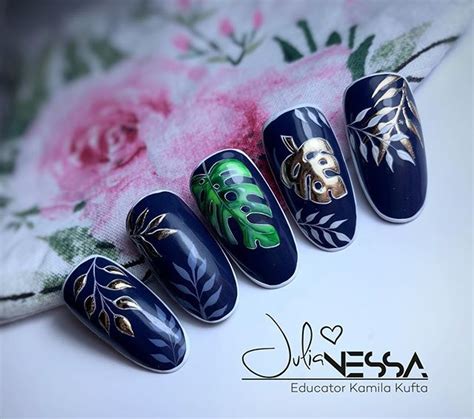 The Nails Are Decorated With Gold And Green Flowers On Blue Nail