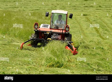 Farmer cutting grass with a tractor Stock Photo - Alamy