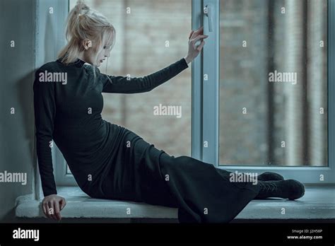 Blonde Woman Lying On The Window Sill And Sad Her Unhappy Stock Photo