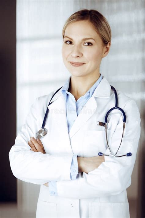 Friendly Female Doctor Standing In Sunny Clinic Portrait Of Cheerful