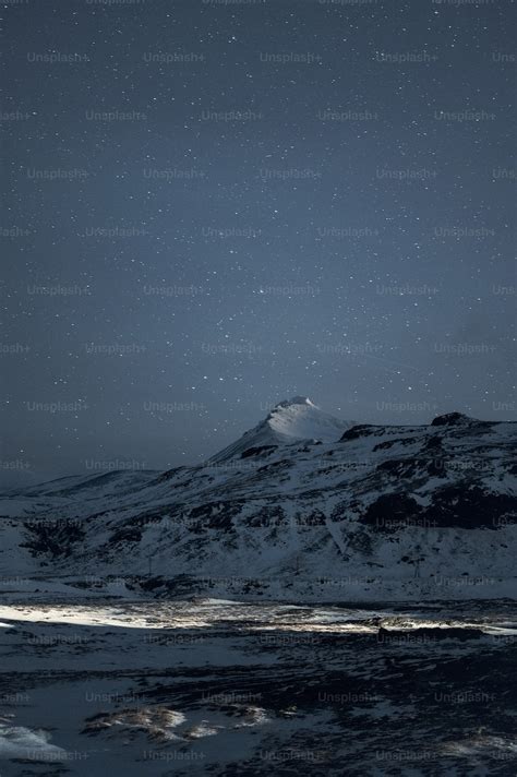 A snow covered mountain under a night sky photo – Starry sky Image on ...