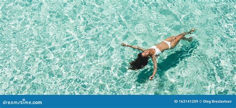 Mujer En Bikini Blanco Sobre Una Superficie Transparente De Agua Turquesa En La Playa Imagen De