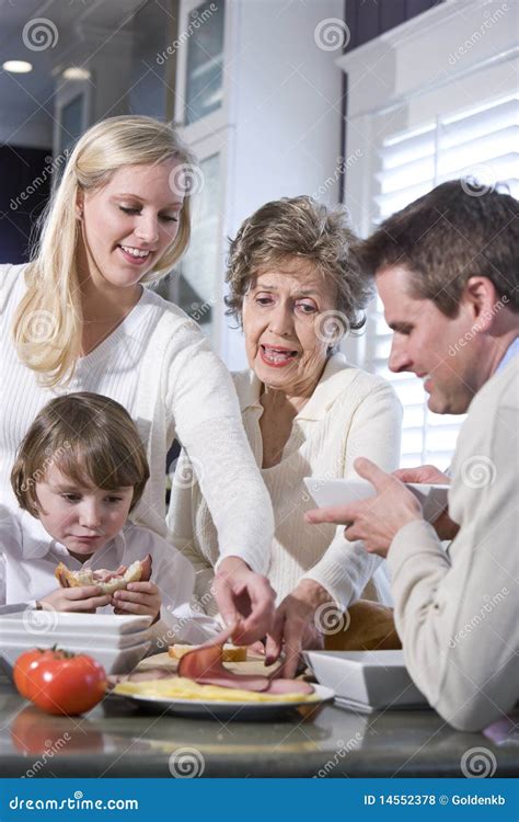 Abuela Con La Familia Que Come El Almuerzo En Cocina Foto De Archivo