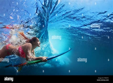 Jeune fille en bikini surfer avec planche de surf sous marine Plongée sous les grandes vagues