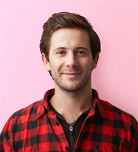 A Man Standing In Front Of A Pink Wall Wearing A Red And Black