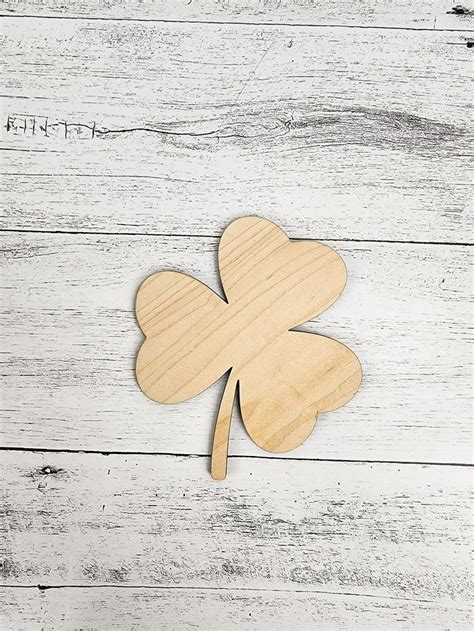 A Four Leaf Clover Shaped Wooden Cutout On A White Painted Wood Planks