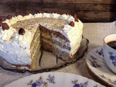 There Is A Cake With White Frosting And Nuts On It Next To A Cup Of Coffee