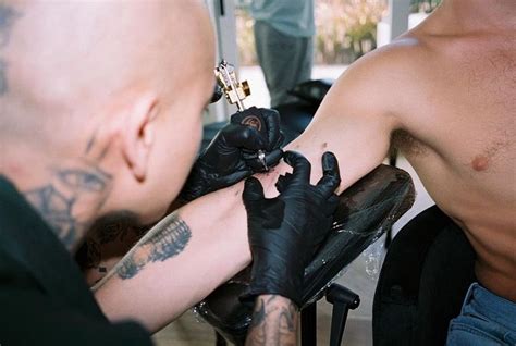 A Man Getting His Arm Tattoo Done By Another Person With Tattoos On