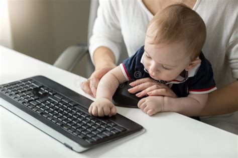 Portrait Of Cute Baby Boy Typing On Computer Keyboard With Mother