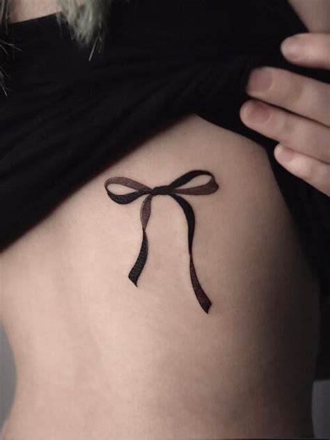 a woman with a tattoo on her stomach that has a bow at the top and bottom