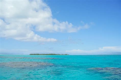 Turquoise Water Of Tropical Ocean With Small Distant Atoll And Coral