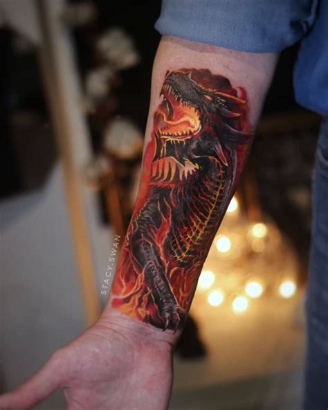 a person with a tattoo on their arm holding up a red and black fire ...