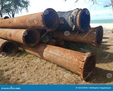 Stack Of Abandoned Rustic Pipeline Laid On The Sand Beach Stock Photo