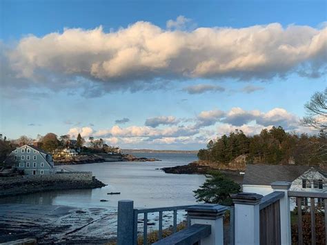 A View Of The Ocean From A Deck In Front Of Some Houses And Clouds Above It