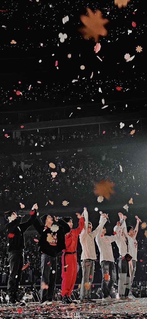 A Group Of People Standing On Top Of A Stage With Confetti In The Air