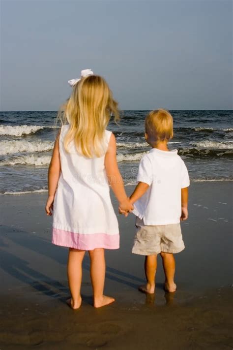 Dos Niños Que Llevan a Cabo Las Manos En La Playa Foto de archivo