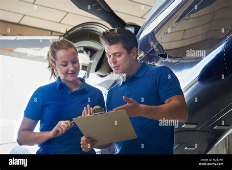 Aero Engineer And Apprentice Working On Helicopter In Hangar Stock