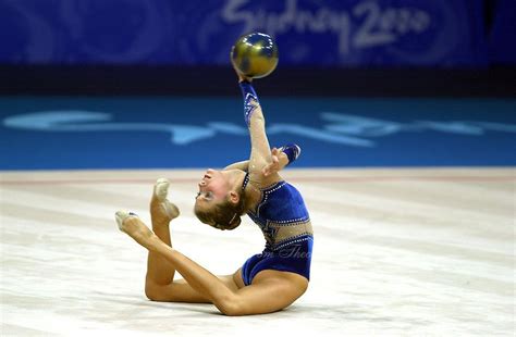 A Woman On The Ground With A Ball In Her Hand And One Leg Up As If To