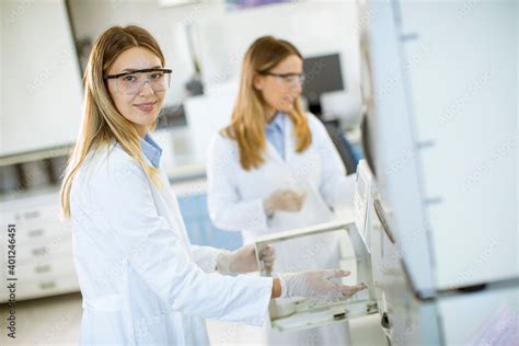 Female Scientists In A White Lab Coat Putting Vial With A Sample For An