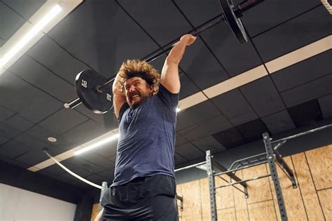 Sosteniendo pesas hombre fuerte está levantando pesas en el gimnasio