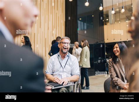 Happy Mature Businessman With Disability Sitting On Wheelchair While