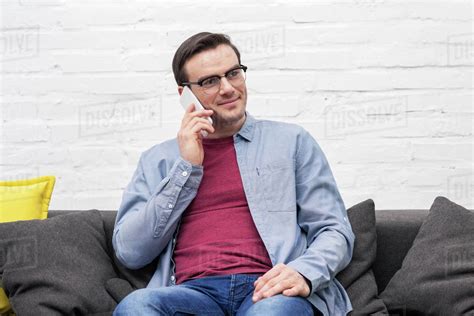 Happy Adult Man Talking By Phone On Couch At Home Stock Photo Dissolve