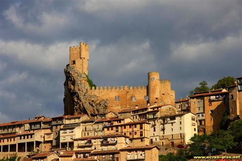 a castle on top of a hill in the middle of town with buildings below it