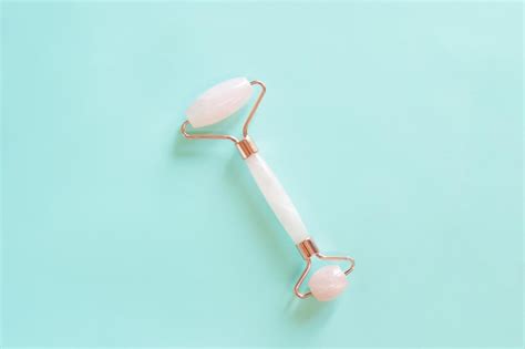 Premium Photo Rose Quartz Facial Massage Roller On A Blue Background