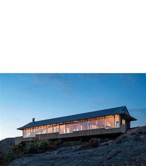 A House On Top Of A Hill With Windows Lit Up In The Evening Sky Above It