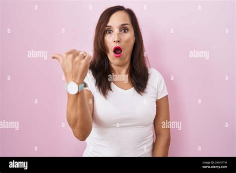 Middle Age Brunette Woman Standing Over Pink Background Surprised