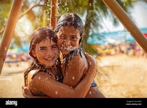 Retrato de dos niñas juntos bajo una ducha al aire libre en la playa