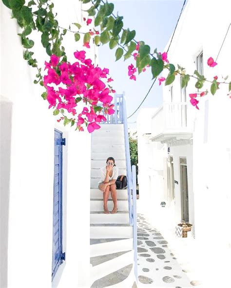 A Woman Sitting On The Steps In Front Of Some Flowers And Buildings