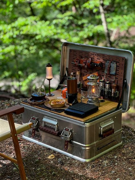 An Open Suitcase Sitting On Top Of A Forest Floor Next To A Chair And Table