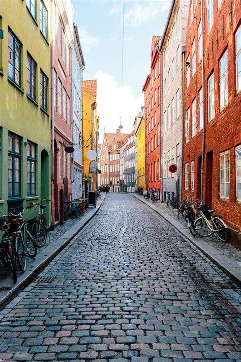 An Empty Cobblestone Street With Bicycles Parked On The Side And