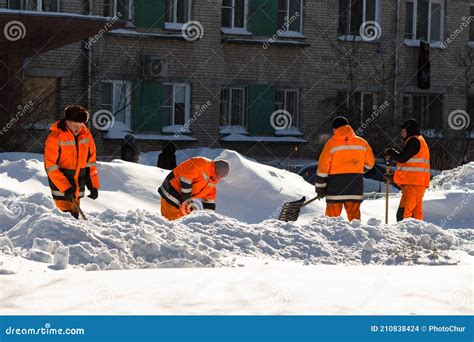 City Utility Workers In Bright Orange Suits Remove Snow From City