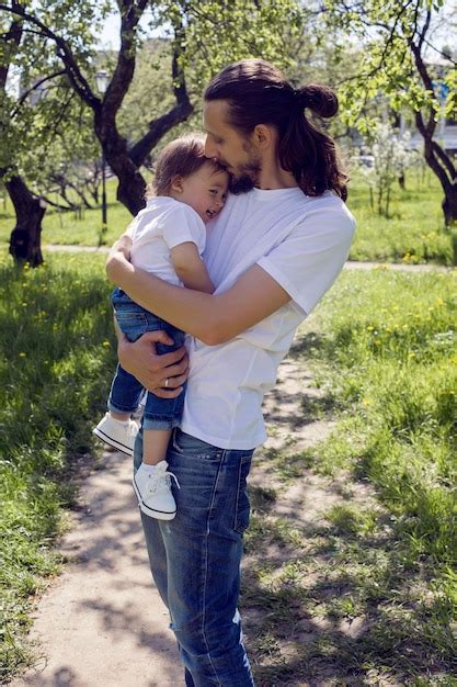 Padre Sostiene A Su Hijo En Sus Brazos En Un Jard N En Flor Foto Premium