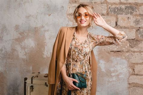 Portrait de jolie femme blonde élégante souriante en manteau beige marchant dans la rue contre