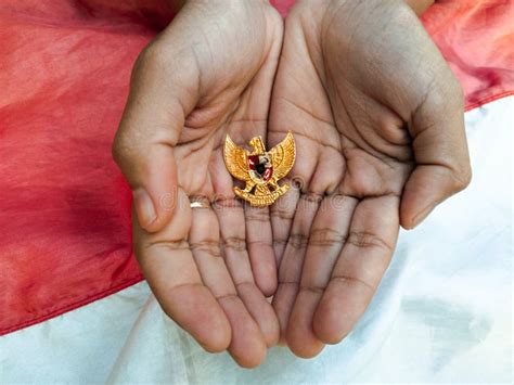 Garuda Pancasila Symbol In Hand With Indonesian Flag Background Stock