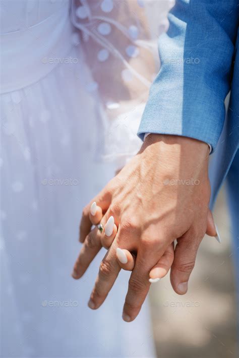 The Bride And Groom Tenderly Hold Hands Between Them Love And