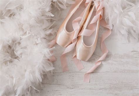 Pink Ballet Pointe Shoes And Feather On White Wood Background Stock