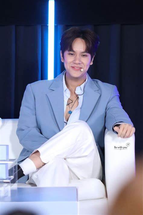 A Man In A Blue Suit Sitting On A White Chair