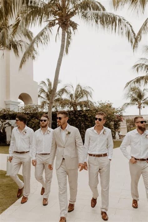 A Group Of Men In White Suits And Sunglasses Walking Down A Sidewalk