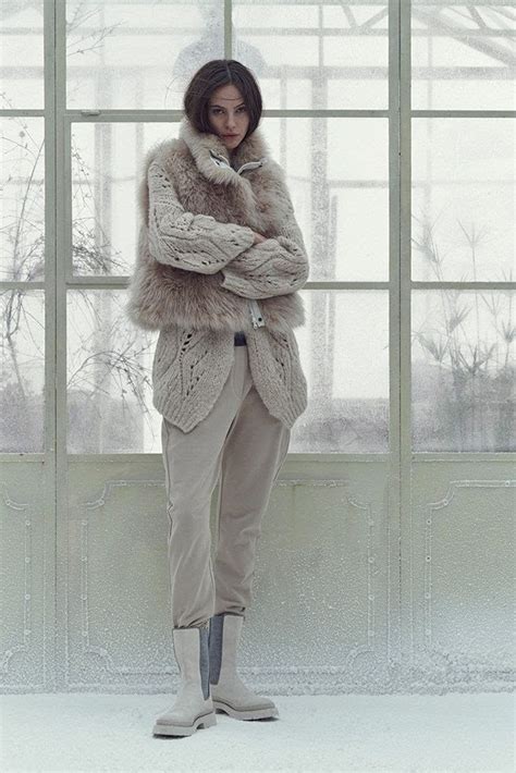 A Woman Standing In Front Of A Window With Her Arms Crossed And Wearing