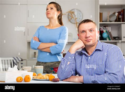 Upset Man Sitting At Table After Quarrel With Wife At The Home Table