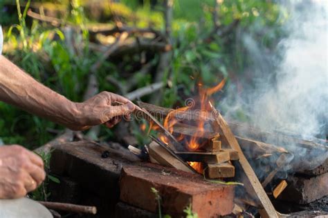 Man Warms His Hands On Fire Burning Wood At Evening In The Forest