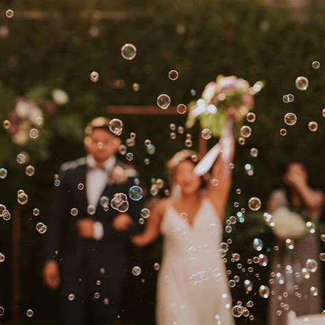 A Bride And Groom Standing In Front Of Bubbles