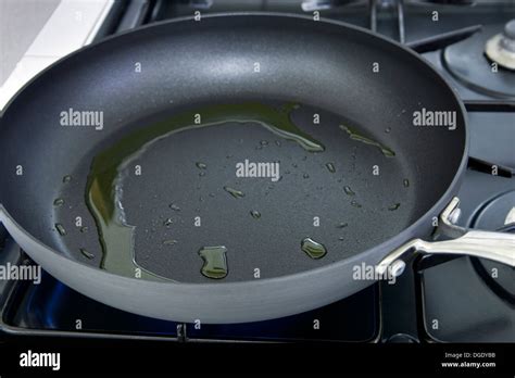 Olive oil heating in frying pan on stove Stock Photo - Alamy