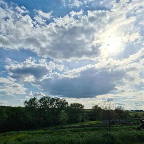 Un cielo nublado sobre un campo con árboles y un campo en primer plano