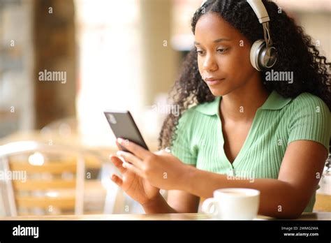 Serious Black Woman Wearing Headphone Listening To Music Using Smart